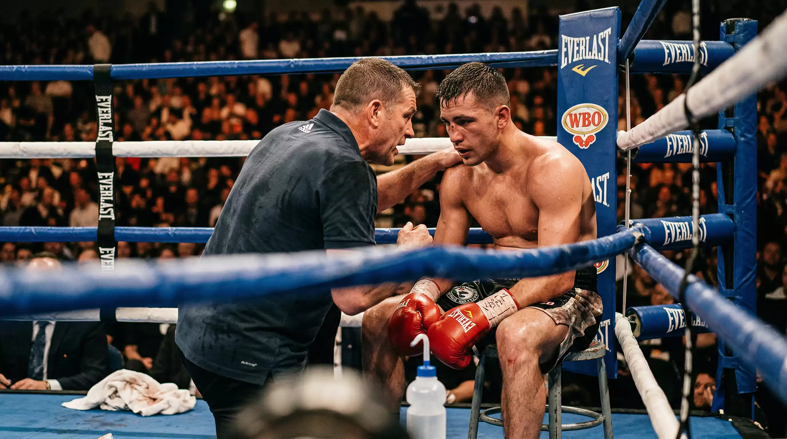 Boxkampf Analyse – Trainer bespricht Strategie mit einem Boxer in der Ecke